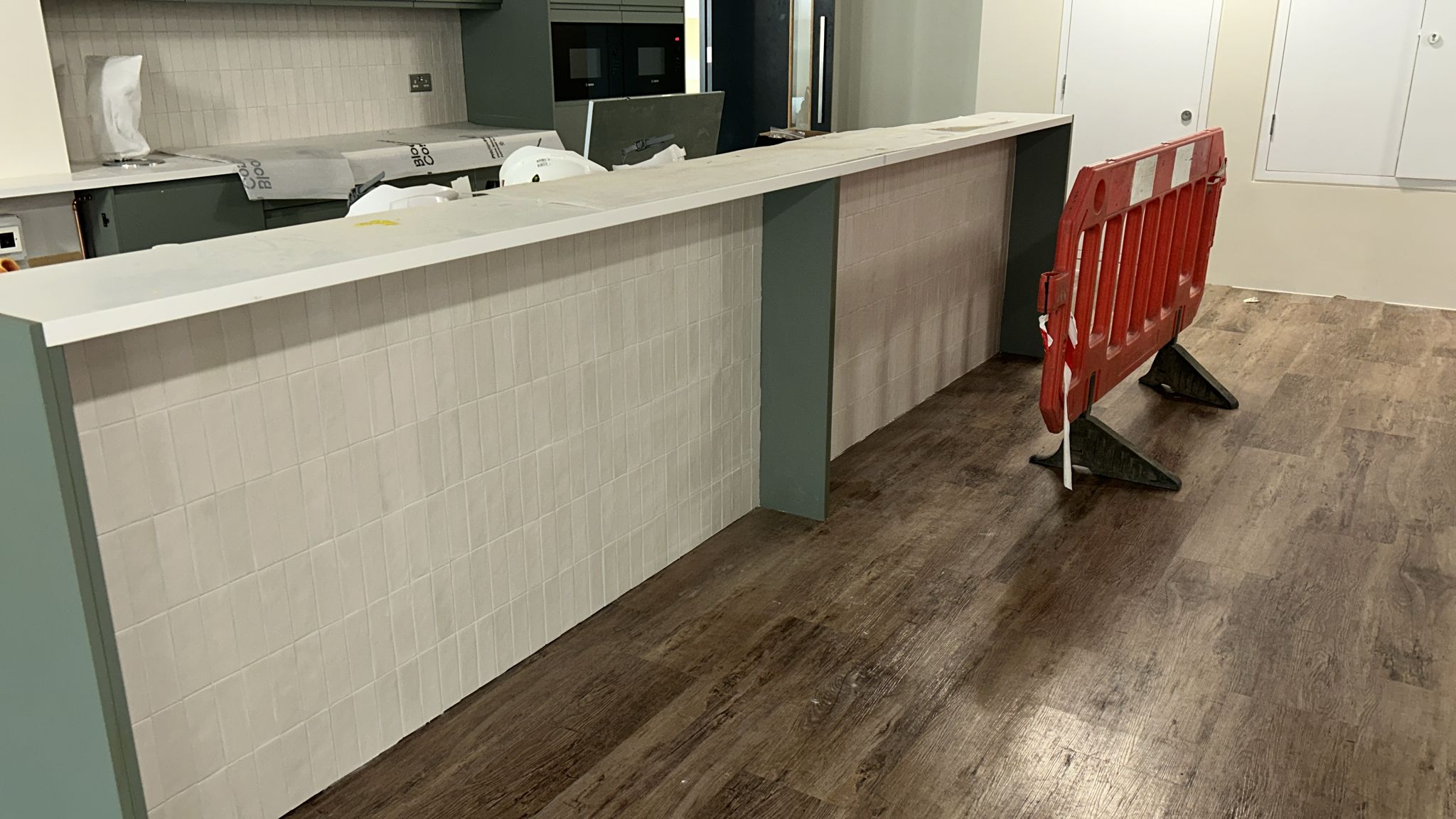 HiMacs breakfast bar with white stack-tile front panel and engineered timber flooring